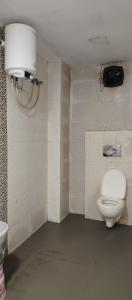 a bathroom with a toilet and a light on the wall at Hotel Renuka Inn A Unite shyam ganga builders in Deoria