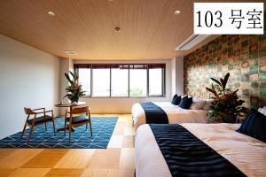 ein Hotelzimmer mit zwei Betten und einem Tisch in der Unterkunft Angelroad Hotel in Tonosho