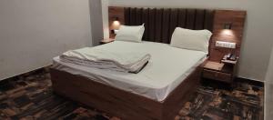 a bedroom with a large bed with white sheets and pillows at Hotel Renuka Inn A Unite shyam ganga builders in Deoria