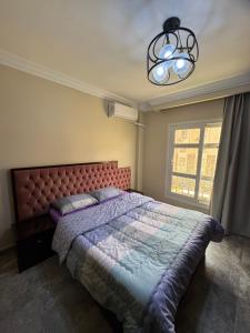a bedroom with a large bed and a chandelier at Privado Modern Apartment Garden View B11 Group114 2BR in Madinaty