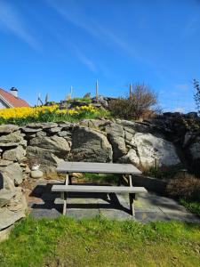 a picnic bench sitting in front of a stone wall at Dugneberg in Karmøy +5 photos