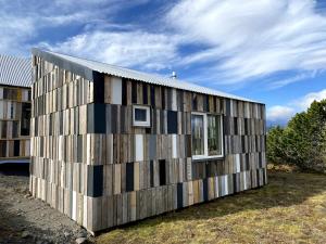 a house clad in wooden panels with windows at Guesthouse With Lake View in Veiðilundur