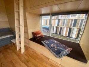 a tiny house with a window and a couch and a rug at Guesthouse With Lake View in Veiðilundur