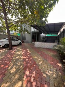 a tree in front of a building with a brick sidewalk at Green Heaven Stay in Surat