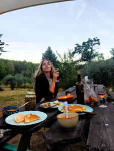 a woman sitting at a picnic table with food and wine at Casa Rural Las Gesillas in Arenas de San Pedro