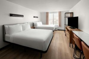 a hotel room with two beds and a flat screen tv at StudioRes by Marriott Mesa in Mesa
