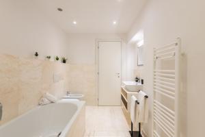a white bathroom with a tub and a sink at Appartamento BePlace - Le Crete in Rapolano Terme +17 photos