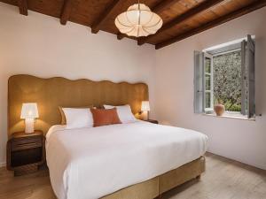 a bedroom with a large white bed and a window at Bellevalia Hydra in Hydra