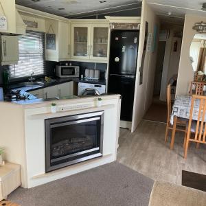 a kitchen with a fireplace and a black refrigerator at Konies Place Golden Anchor Free WiFi Bedding Included in Chapel Saint Leonards