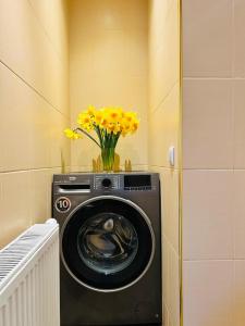 eine Waschmaschine mit einer Vase gelber Blumen darauf in der Unterkunft Hotel K.V.N. in Ragaciems