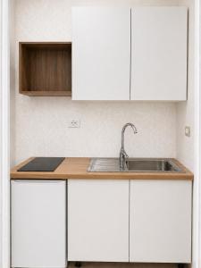 a kitchen with white cabinets and a sink at Vila Familjare Memushi in Ksamil