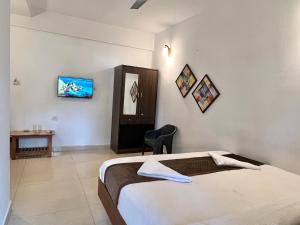 a bedroom with a bed and a table and a tv at Aura Calangute in Calangute