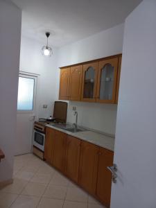 a kitchen with wooden cabinets and a sink at Vila Familjare Memushi in Ksamil +29 photos