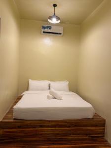 a bedroom with a bed with white sheets and a fan at 9 Keys Inn in San Vicente