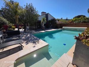 a swimming pool with two chairs in a yard at Spacieuse villa au calme avec grande piscine in Bormes-les-Mimosas