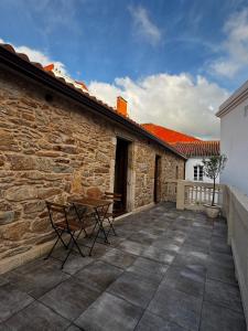 a patio with a table and a stone building at Casa Erundina in Camariñas