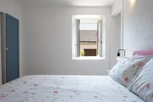 a white bedroom with a bed and a window at Casa La Barancina in Cittiglio