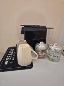 a coffee maker on a counter with two jars and a cup at Airport city center 2 in Spata
