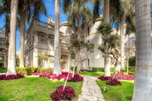 a large white building with palm trees and flowers at El Safwa Resort New Cairo in Cairo