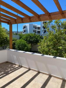 a patio with a wooden pergola and trees at CasaKOS in Kos