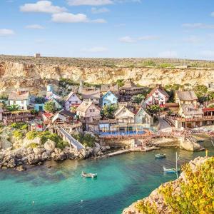 a group of houses on a hill next to the water at Victoria by Petit Chic in Mellieħa