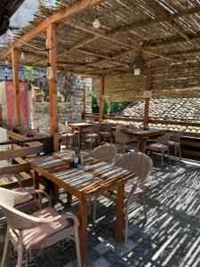 a restaurant with wooden tables and chairs and a roof at Bujtina Bega in Berat