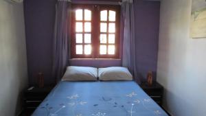 a small bedroom with a bed with a window at Pousada da Lucinha in Canoa Quebrada