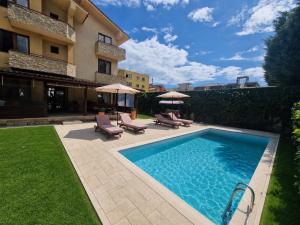 a swimming pool with chairs and umbrellas next to a building at Vila Eclipse Mamaia nord in Mamaia Sat/Năvodari