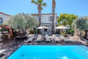 a pool with chairs and umbrellas next to a building at B House Alaçatı in Alaçatı