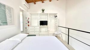 a white bedroom with a bed and a tv at Civico5 - Spazioso appartamento 110 mq a Cefalù in Cefalù