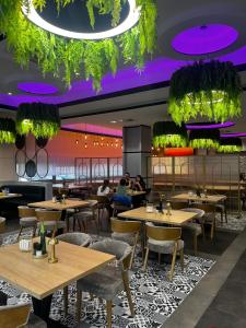 a restaurant with wooden tables and chairs and purple lighting at Hotel Aquarius Restaurant Wellness Spa in Ciechocinek
