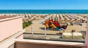 a beach with a playground and chairs and umbrellas at Hotel Maria Luisa in Rimini