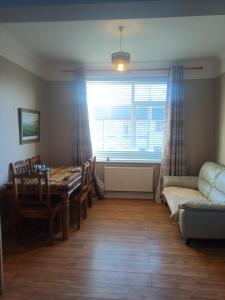 a dining room with a table and a window and a couch at Glenlara House in Youghal