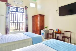 a bedroom with two beds and a tv and a window at Nhà nghỉ Việt Mến in Sầm Sơn