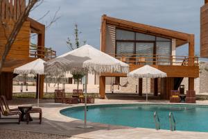a swimming pool with two umbrellas and a house at Good Days Habitat Soma Bay in Hurghada