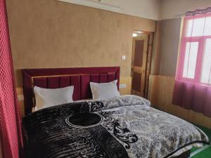 a bedroom with a bed with a table on it at Ochre Spiti in Lara