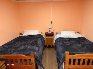 a bedroom with two beds and a table with a lamp at Casa Oruro Valvic in Oruro