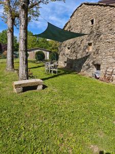a green umbrella hanging from a tree next to a stone building at Vallicella House in Fanano