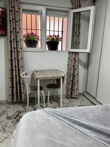a bedroom with a table and chairs and two windows at Aladín House Vinaròs playa in Vinarós