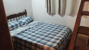 a bedroom with a bed with a blue plaid at Cabana in Santo Antônio do Pinhal