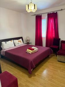 a bedroom with a bed with purple sheets and red curtains at Villa Palma in Prijevor