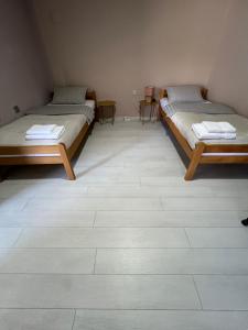 two beds in a room with a tile floor at Apartmani Gala Foča in Foča