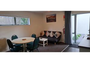 a living room with a couch and a table and chairs at Alcala Motor Lodge in Christchurch