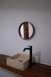 a stone sink with a mirror on a wooden counter at Buggei Surfcamp Mentawai in Katiet