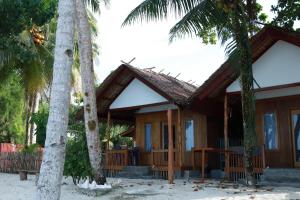a house on the beach with two palm trees at Buggei Surfcamp Mentawai in Katiet