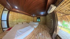 a large bed in a room with a wooden floor at Pu Luong Roots Homestay in Pu Luong