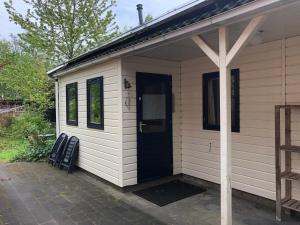 a white house with a black door and a chair at De Merel in Pieterburen