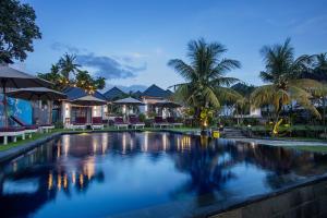 a swimming pool in front of a resort with palm trees at Secret Point Huts in Nusa Lembongan