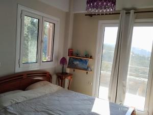 a bedroom with a bed and two windows at To Fournaraki in Gialiskari