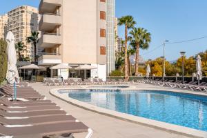 a swimming pool with chairs and umbrellas next to a building at Primavera Loix in Benidorm